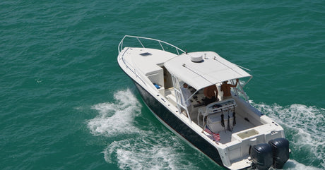 An overhead view of a fishing boat with an awning and American flag sailing over the water during the day.
