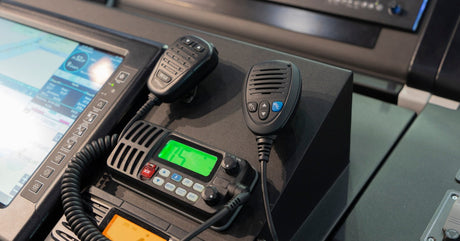 A navigation terminal on a boat with a display in the middle of the dash and two handheld radios attached.