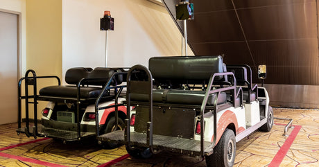 Two golf carts with mirrors sirens attached to the tops of them sitting inside of a taped off area in an airport.