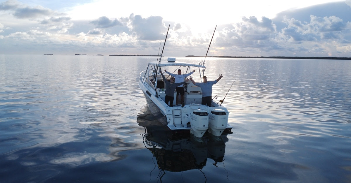 A family standing on the back of a boat posing with their hands out during a fishing trip on the open ocean.