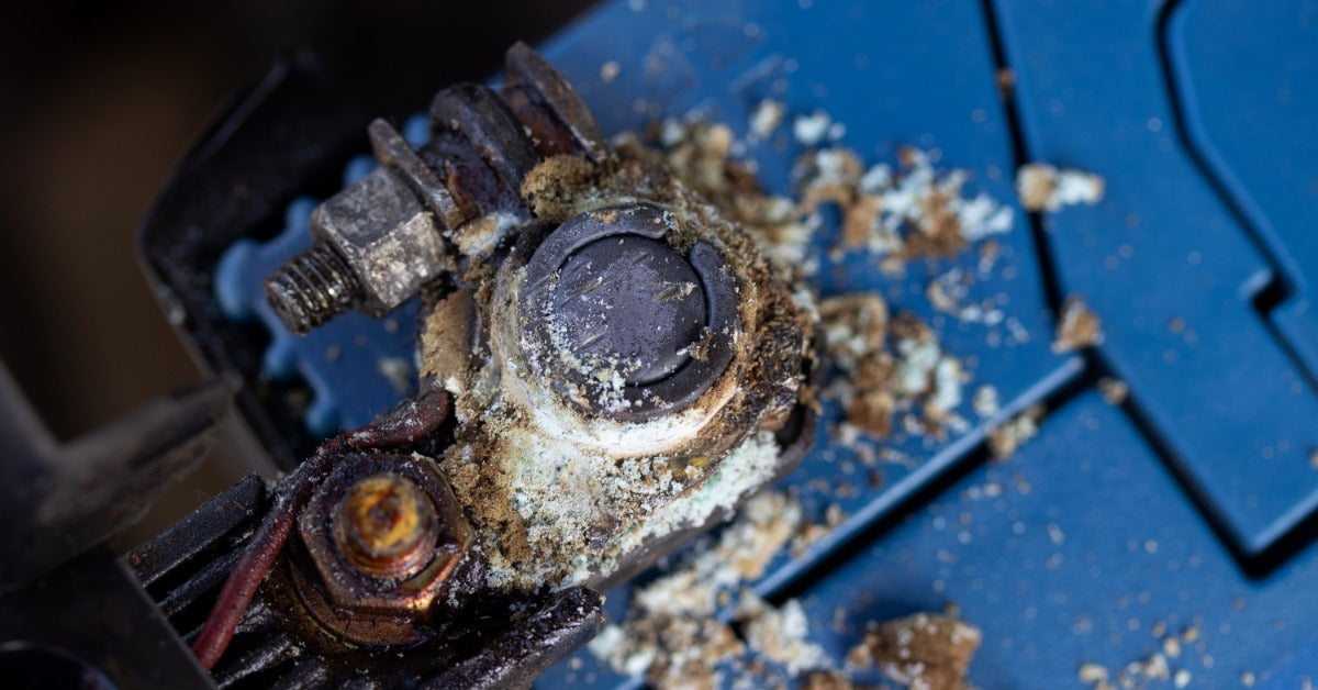 An aerial view shows a blue battery that has tiny white and brown crystals around the terminal.