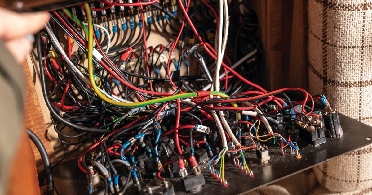 An open panel behind a seating area. The panel houses a wide array of wires in different colors.