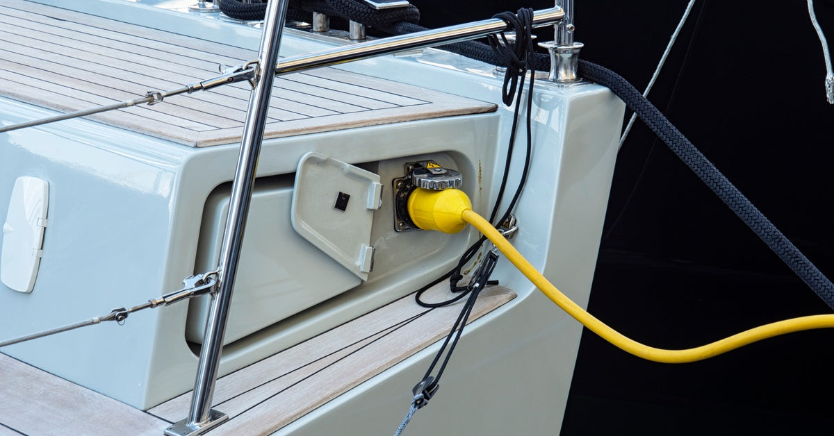 A yellow charging cord reaching over the water to connect with a ship's on-board charging port to give it power.
