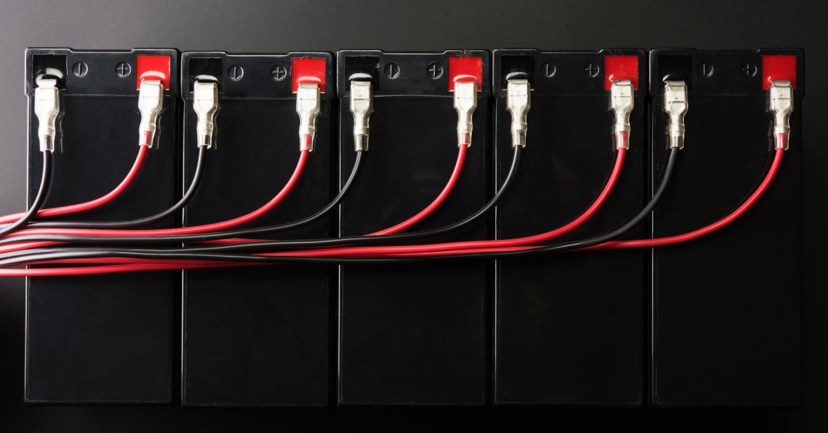 A row of black batteries, each connected to a red wire and a black wire. The wires all gather to the left of the row.