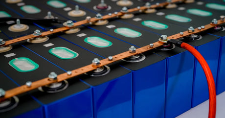 Several rows of connected electric lithium batteries connected vita metal pieces on their silver bolts with one wire.